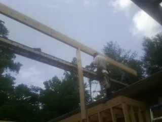Carpenter setting a ridge beam over a new addition frame — Ice Dam Removal by Roofing Brothers in Machesney Park