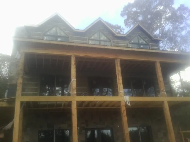 Dormers and porch framing on a large log home under construction — Roof Coating work by our crew in Machesney Park