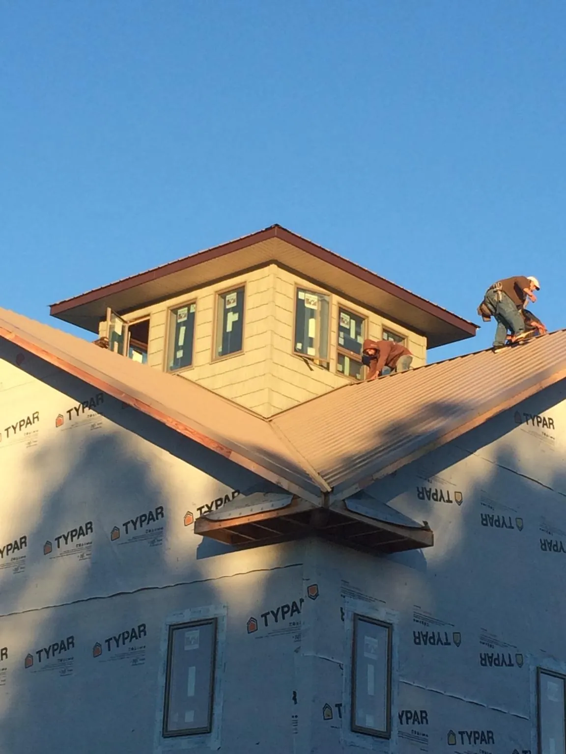Roofers working around a rooftop cupola on a new metal roof at sunset — Roof Waterproofing in Machesney Park by Roofing Brothers
